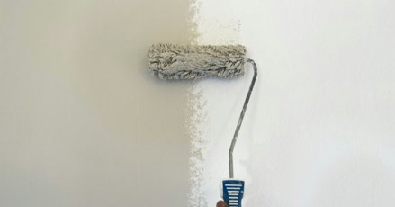 a person using a paint roller to paint a wall